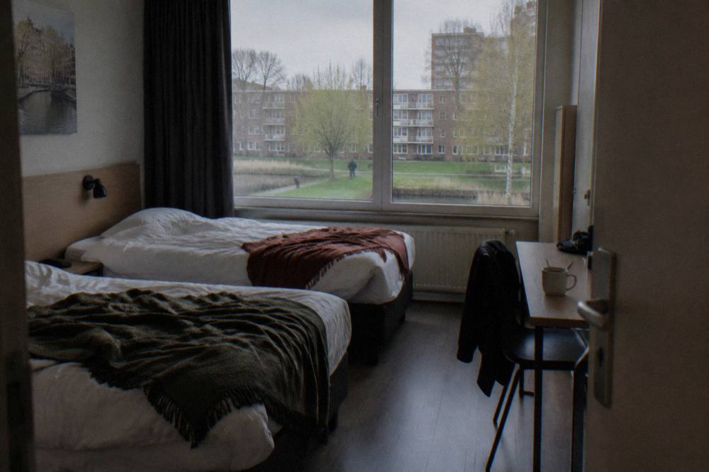 Modern budget hotel room with two single beds and a small desk under a window